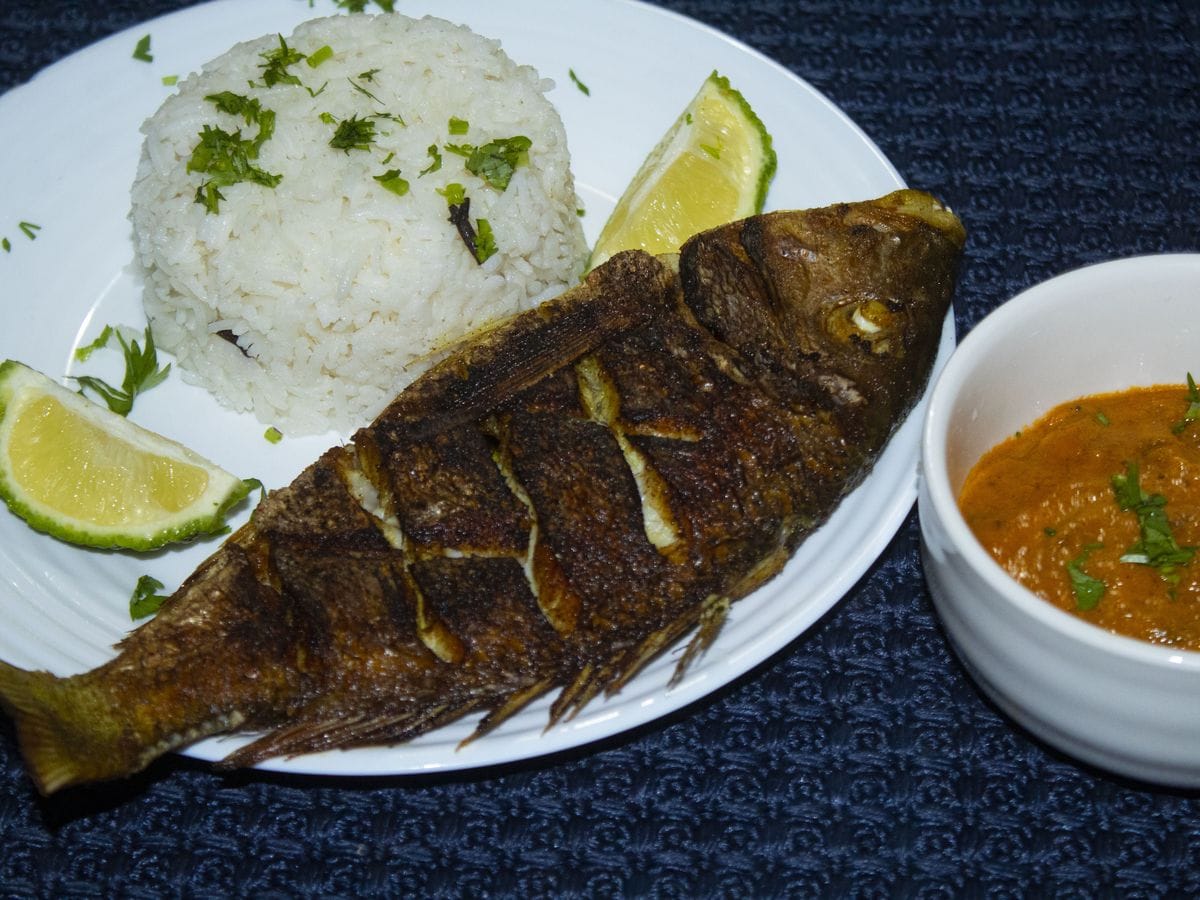 Close-up of grilled whole fish with rice and coconut curry — authentic Swahili coastal cuisine by Chef Angela